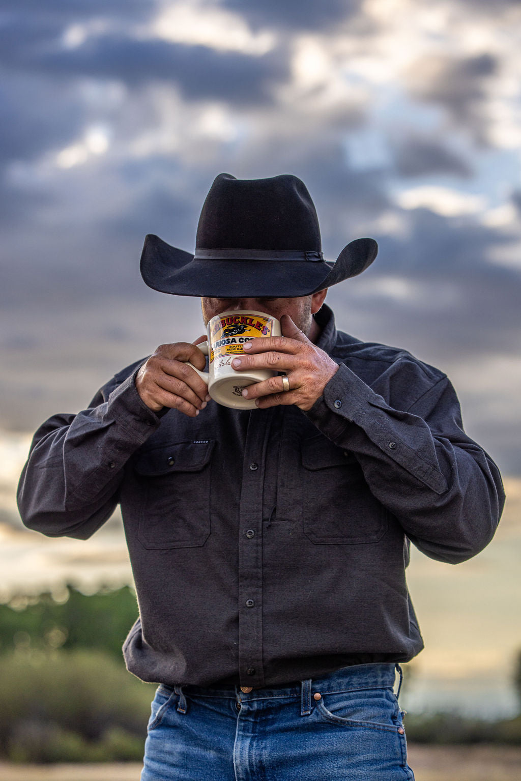 A rancher sipping coffee from an Arbuckles' Ariosa mug