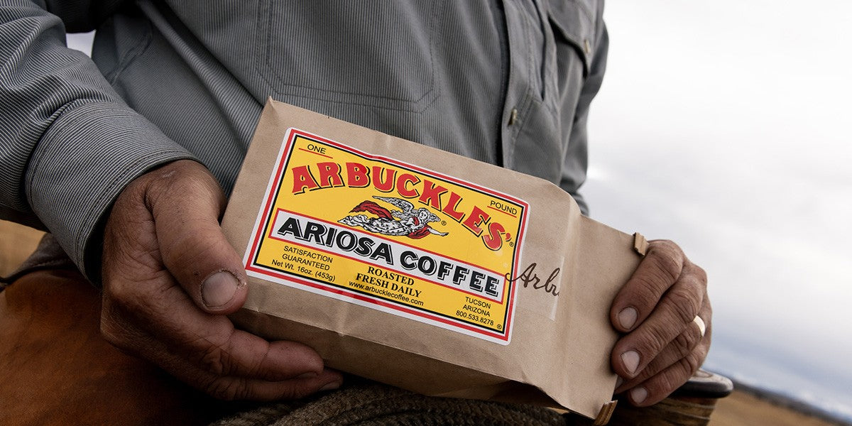 A rancher holding a bag of Arbuckles' Ariosa coffee in the saddle