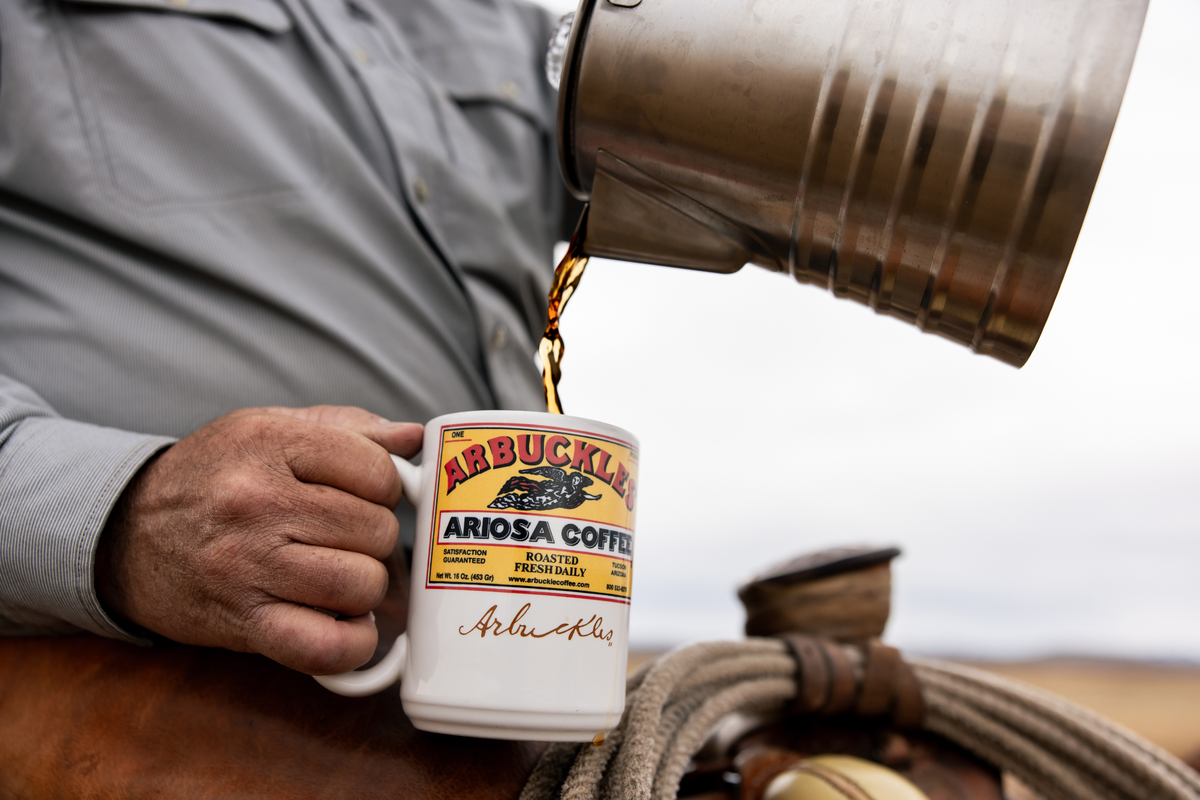 Coffee poured from a camp pot into an Arbuckle's Ariosa mug